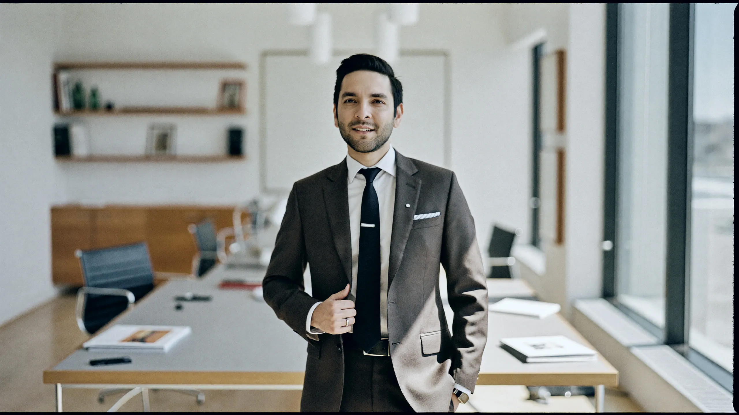 A senior operator standing in a window-lit boardroom, ready for the work