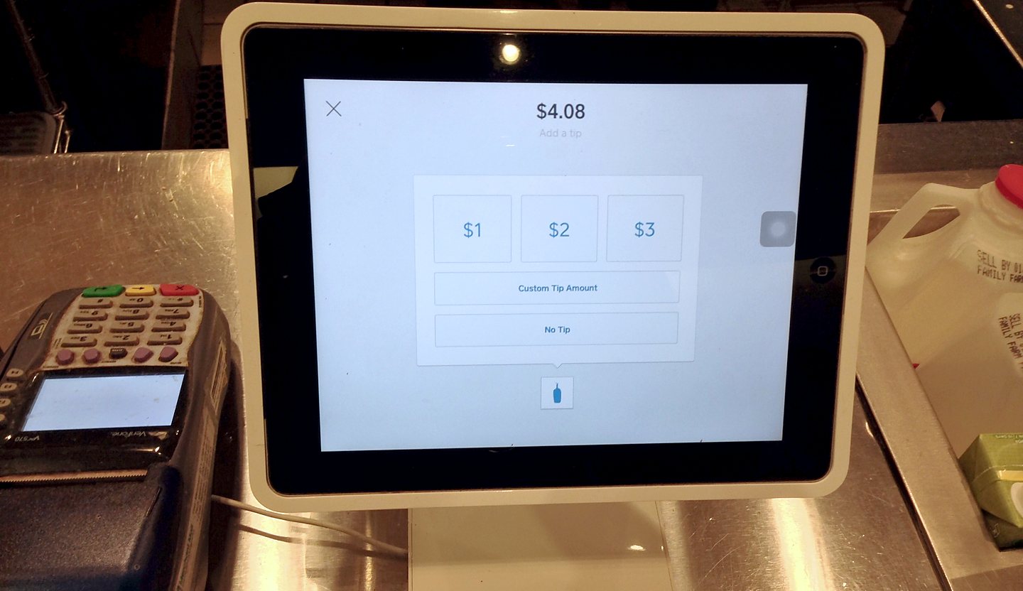 A coffee shop checkout with an iPad point-of-sale mid-transaction and a card terminal beside it
